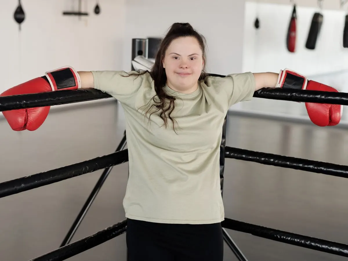 A woman with Down syndrome wearing boxing gloves in a gym